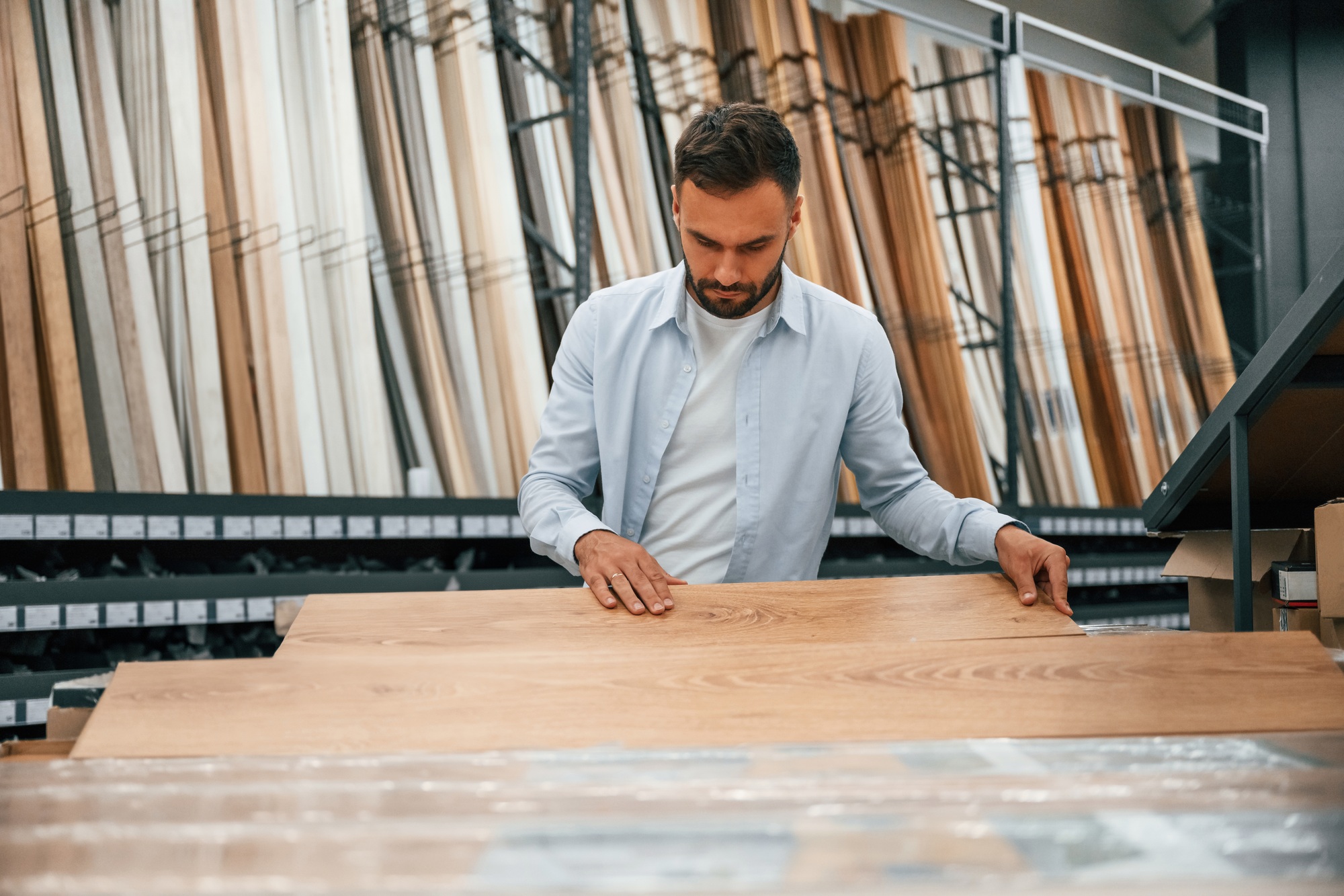 Parquet, choosing. Man is in the hardware shop